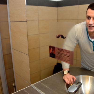 Mann wäscht sich die Hände in Restaurant Toilette und sieht Spiegel mit Werbe Aufkleber