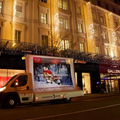 beleuchtetes 16 Bogen Plakat auf weissem Auto mit Werbung für Galleria nachts im Großstadtverkehr