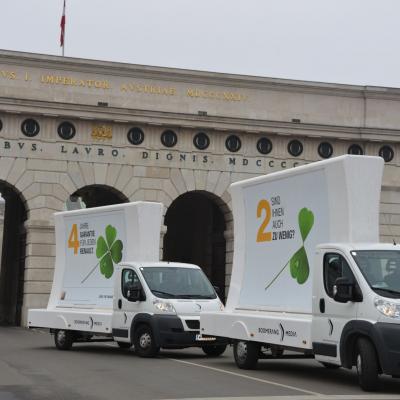 2 mobile Billboards fahren durch das großes Tor bei der Hofburg
