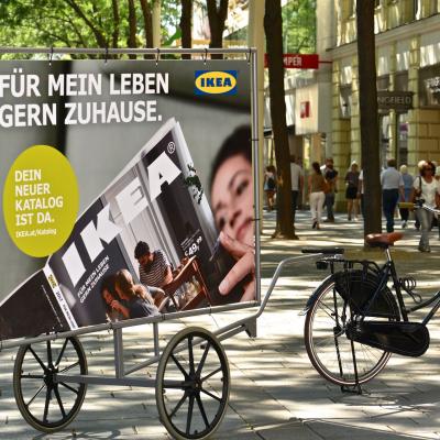 Werbung / Plakat für den Ikea Katalog auf einem Gestell mit Rädern in der Stadt